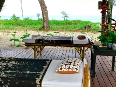 Ontspannende buitenspa tafel met uitzicht op groen landschap en strand.