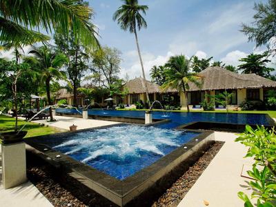 Modern pool area with palm trees and cabanas in a tropical resort.