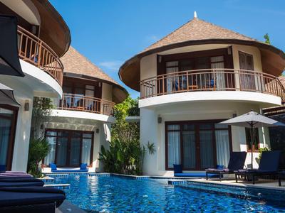 Hotel with round bungalows and pool under clear blue sky