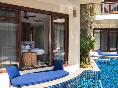 Patio lussuoso con sdraio blu e piscina privata di fronte a una camera d'hotel.