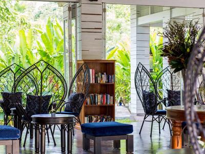 Gezellige zithoek met stoelen en boekenplank in een lichte, open ruimte met uitzicht op groen.