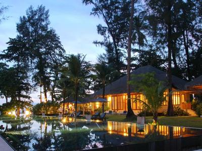 Luxe hotel met verlicht zwembad omgeven door palmbomen bij zonsondergang.