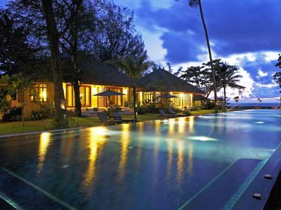 Verlicht resort met lang zwembad bij zonsondergang en palmbomen