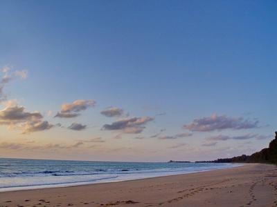 Leeg zandstrand met kalme zee en blauwe lucht bij zonsondergang