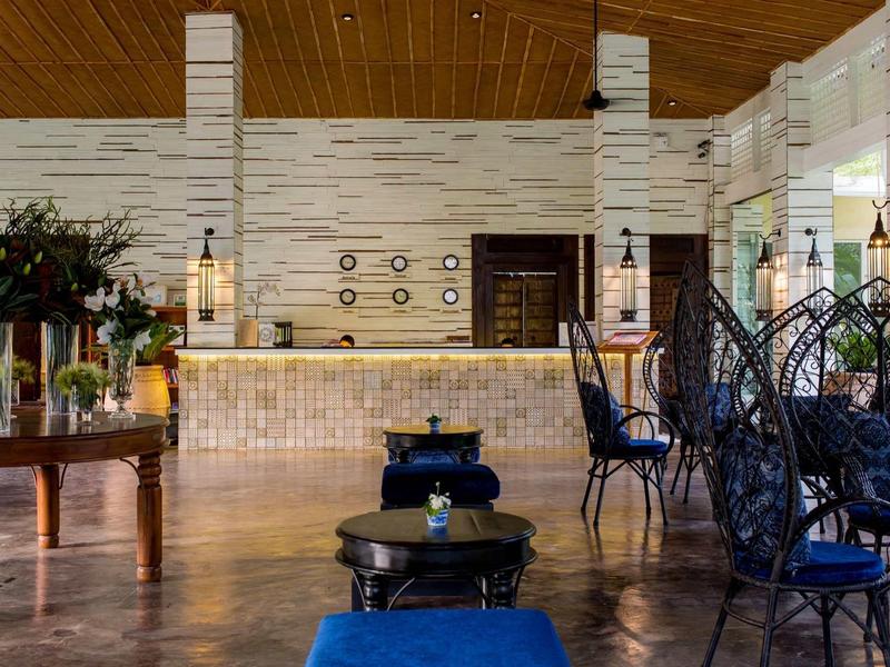 Interieur van een stijlvolle hotelhal met blauw beklede stoelen en decoratieve planten.