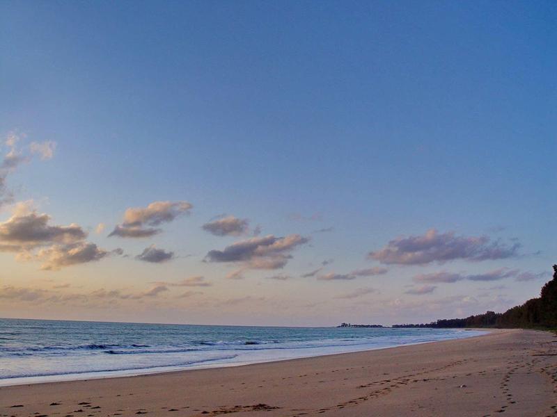 Leeg zandstrand met kalme zee en blauwe lucht bij zonsondergang