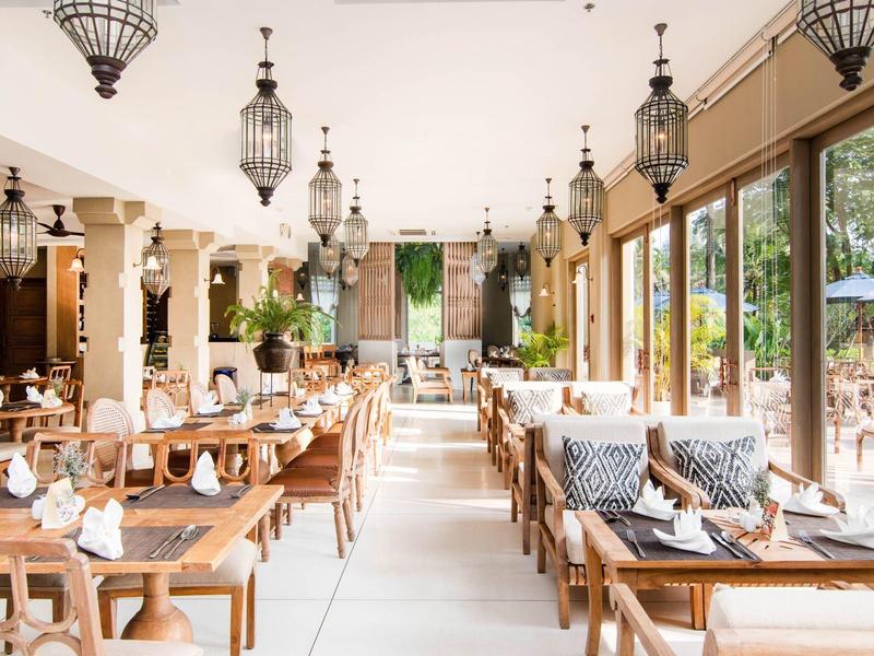 Restaurant lumineux avec mobilier en bois et grandes fenêtres donnant sur une terrasse.