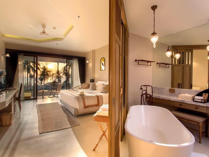 Chambre d'hôtel moderne avec balcon et baignoire autoportante dans la salle de bain.