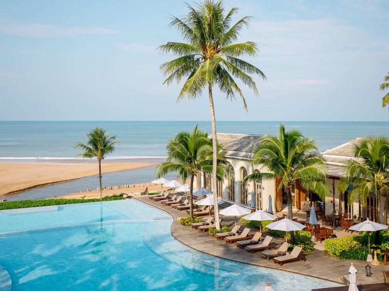 Zone de piscine luxueuse avec des palmiers surplombant la plage et l'océan