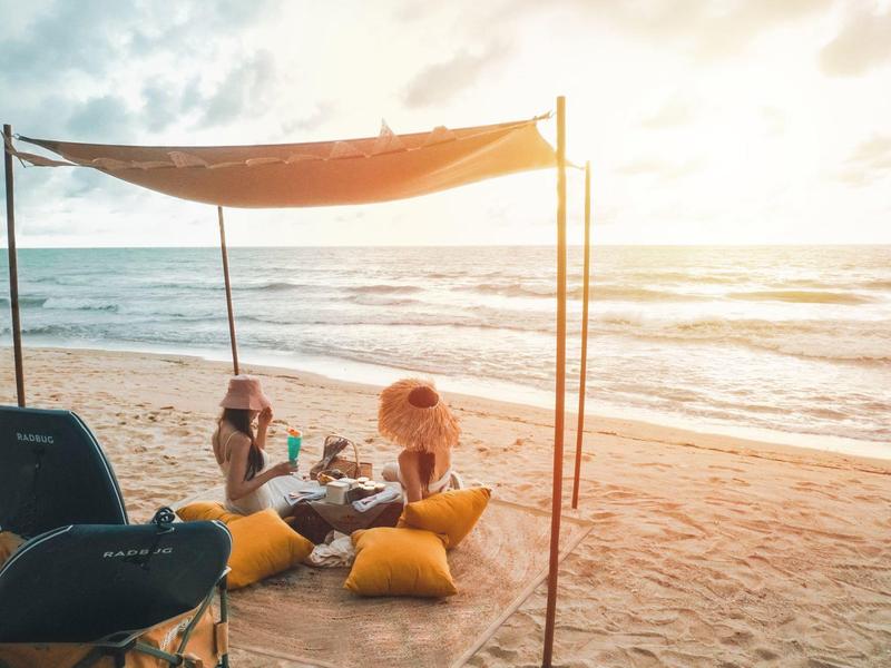 Deux personnes se détendent sous un auvent sur la plage avec vue sur la mer.
