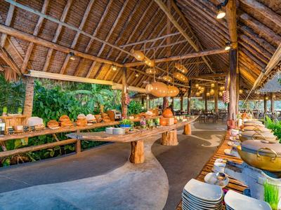 Buffet rustico all'aperto con struttura in legno e vegetazione tropicale sullo sfondo.