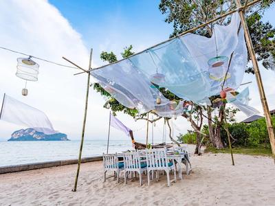 Miejsce do jedzenia na plaży z stołami i krzesłami pod przezroczystym daszkiem, widok na morze