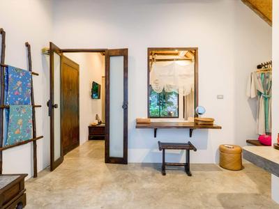 Camera d'hotel luminosa con mobili in legno, specchio e porta asciugamani a muro.