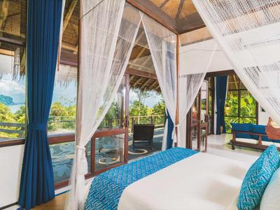 Camera da letto lussuosa con zanzariera, tende blu e vista su alberi verdi.