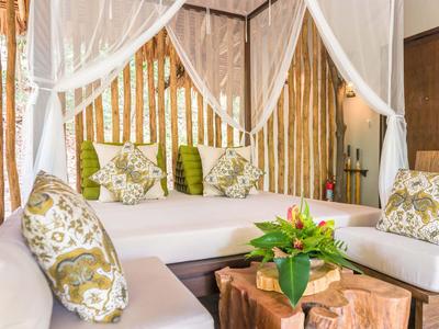 Gemütliche Sitzecke mit Kissen und Holztisch, dekoriert mit Blumen, in einem Hotelzimmer.