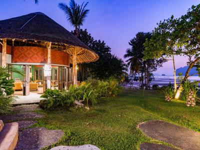 Wieczorny widok w tropikalnym ośrodku z okrągłą chatą i widokiem na morze.