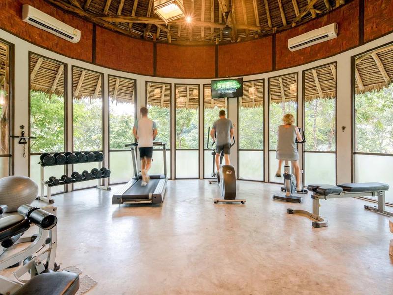 Palestra luminosa con grandi finestre e tre persone su tapis roulant