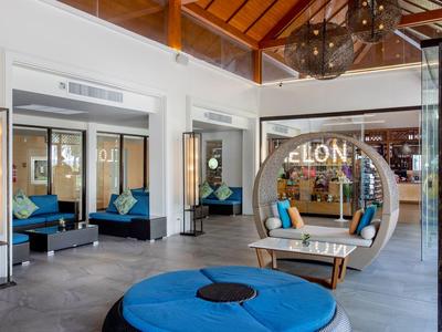 Modern hotel lobby with blue seating and hanging round bed under wooden ceiling.
