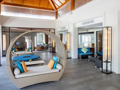 Moderní odpočinková zóna s kulatou pohovkou, barevnými polštáři a přirozeným světlem v hotelu.