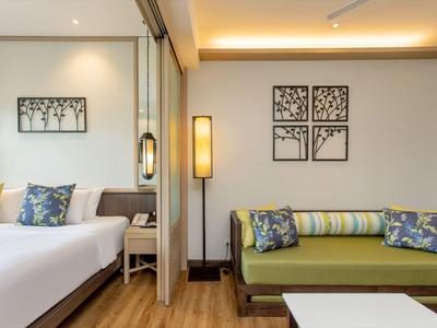 Modern hotel room with bed, sofa, and wall decor.