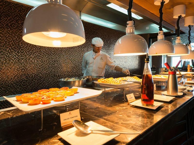 Buffet with bread rolls and drinks displayed in a modern hotel restaurant