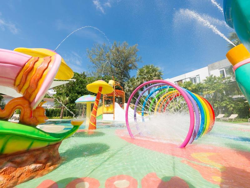 Colorful water park with slides and spray arches under blue sky.