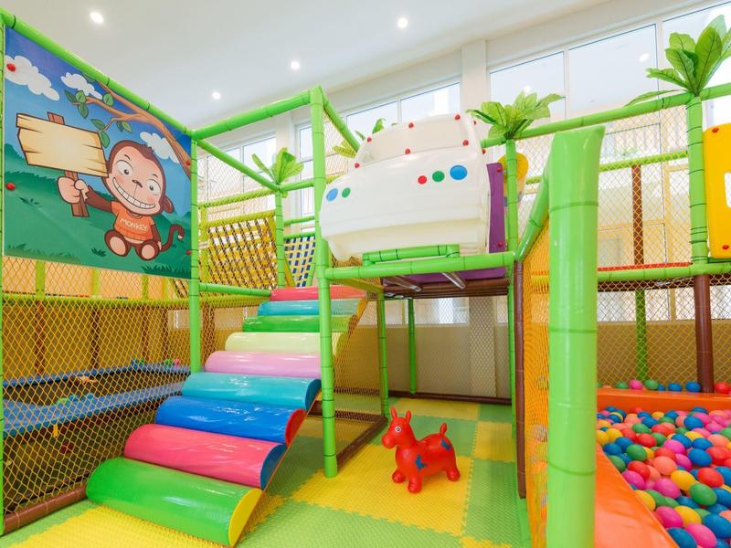Bright indoor playground with colorful climbing ramps and ball pit for children.