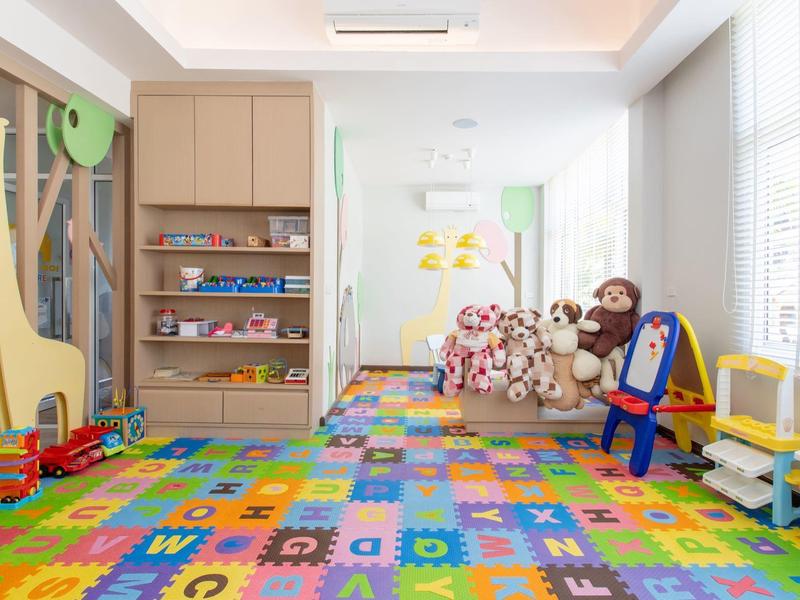 Children's playroom with colorful letter carpet, toys, and large stuffed animals.