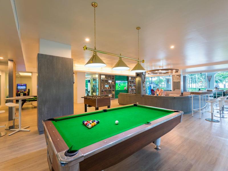 Modern recreation area with a billiard table, counter, and seating in a hotel.
