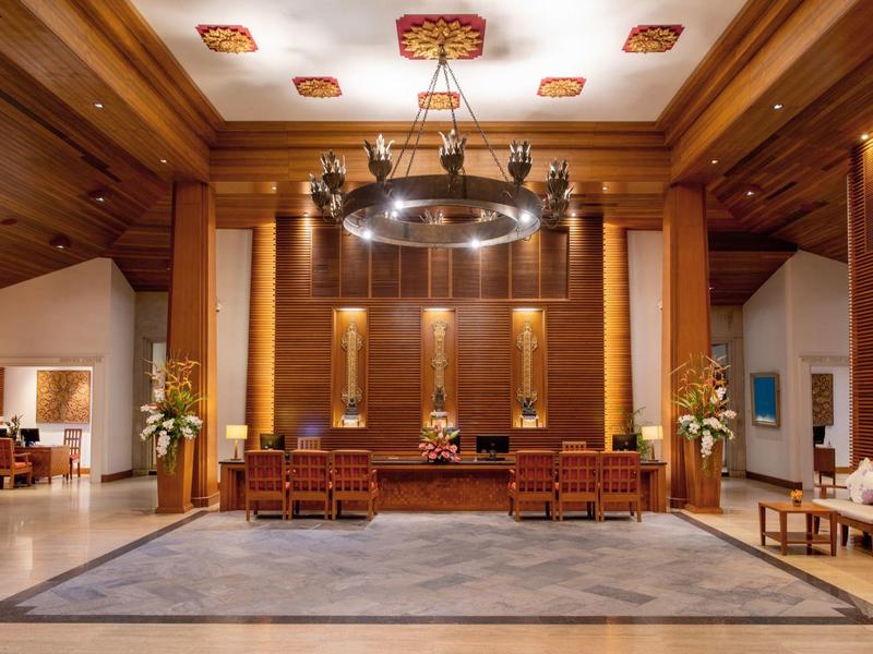 Elegant hotel lobby with wooden paneling, chandelier, and seating area.