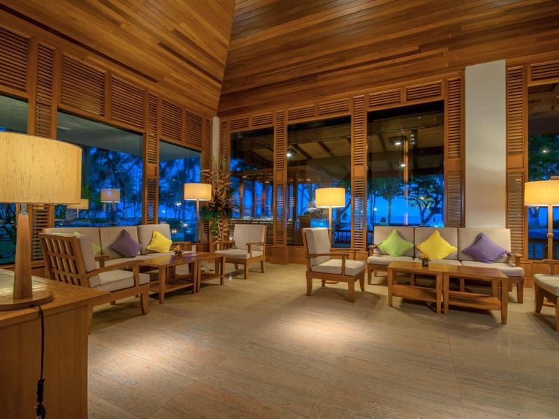 Cozy hotel lounge with wooden walls, armchairs, and warm lighting at dusk.