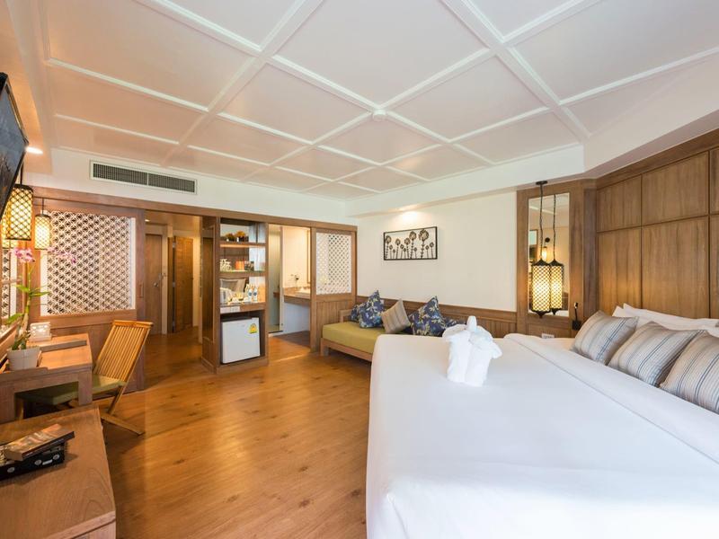 Cozy hotel room with double bed, wooden floor, and seating area with TV.