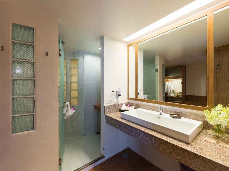 Modern bathroom with large mirror, sink, and shower with glass block wall.
