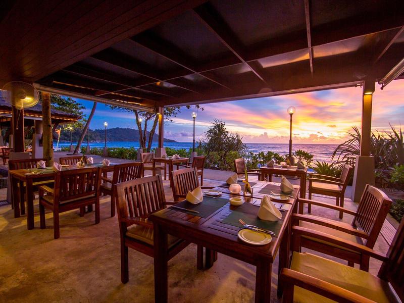 Cozy restaurant with wooden chairs and tables at sunset overlooking the sea.