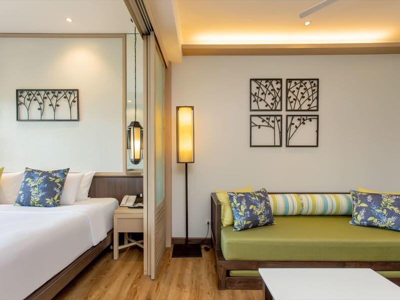 Modern hotel room with bed, sofa, and wall decor.