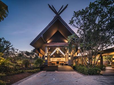 Oświetlony bungalow z otwartą przestrzenią do siedzenia otoczony roślinami o zmierzchu