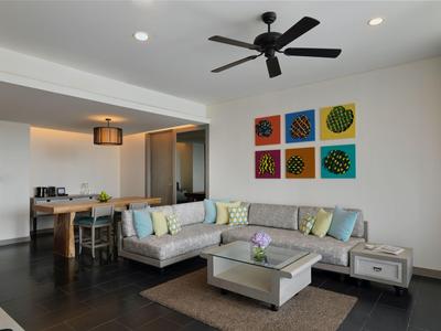 Nowoczesna część wypoczynkowa w hotelu z sofą, szklanym stołem i kolorową dekoracją ścienną.