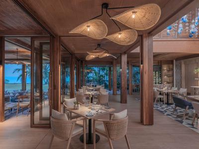 Nowoczesna restauracja z drewnianymi akcentami i widokiem na morze o zmierzchu.