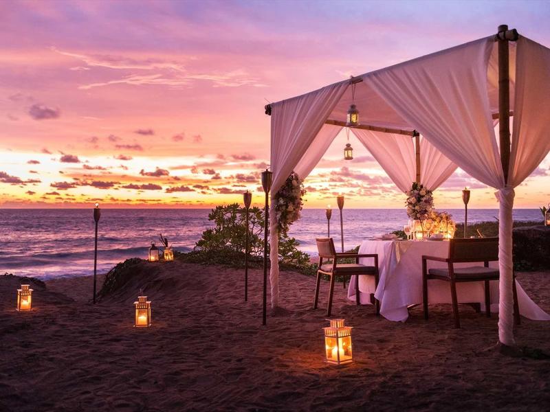 Tente de dîner romantique sur la plage au coucher du soleil avec des lanternes