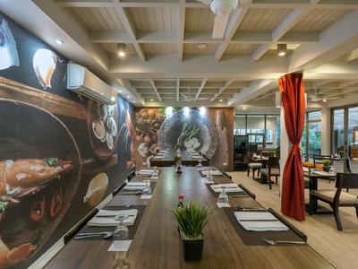 Moderní hotelová restaurace s dlouhým dřevěným stolem, nástěnným uměním a atmosférickým osvětlením.