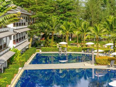 Hotel complex with multiple pools, lounge chairs, and tropical palm trees in the garden area.