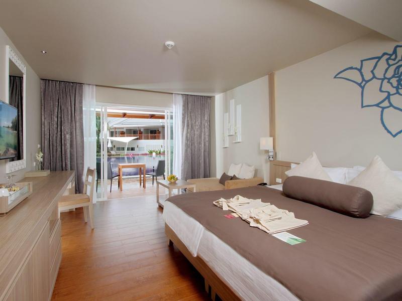 Moderne hotelkamer met tweepersoonsbed, houten vloer en balkon met zitgedeelte en zeezicht.