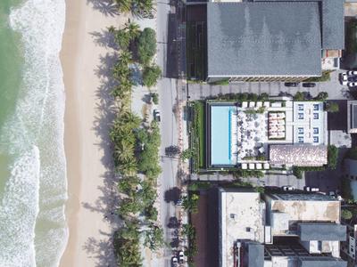 Widok z góry na plażę obok ulicy z hotelami i basenami.