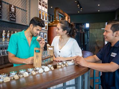 Drei Personen probieren in einer Bar verschiedene Kaffeesorten in kleinen Tassen.