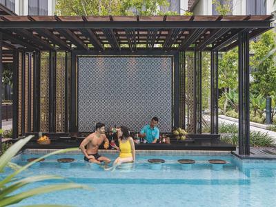 Ludzie relaksują się w basenie z zadaszonym miejscem do siedzenia obok hotelu.