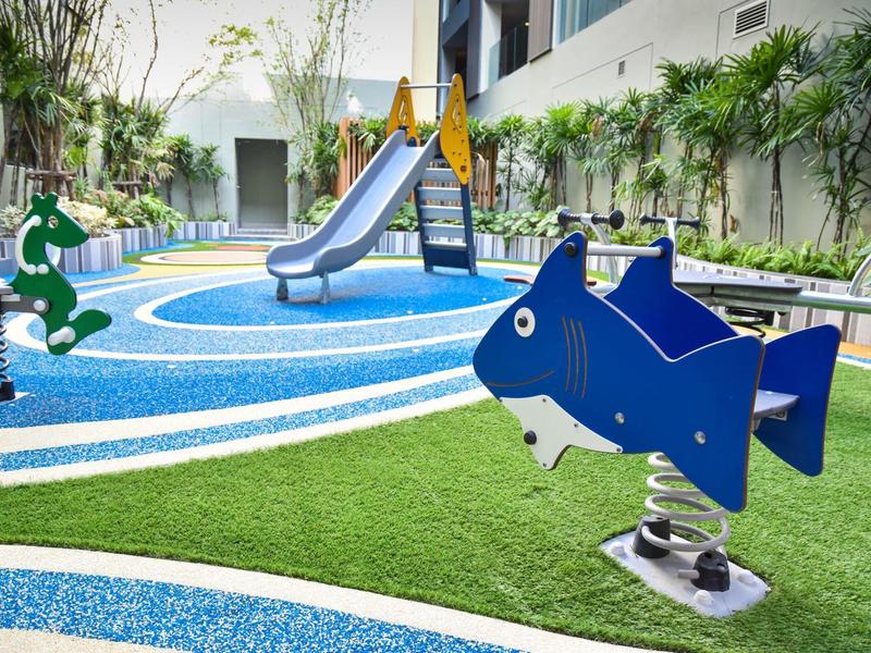 Kolorowy plac zabaw dla dzieci z zjeżdżalnią i sprężynowymi zabawkami w hotelowym ogrodzie.