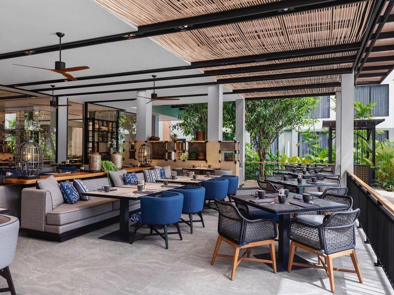 Przestronny zadaszony taras hotelowy z nowoczesnymi miejscami do siedzenia i zielonym widokiem.