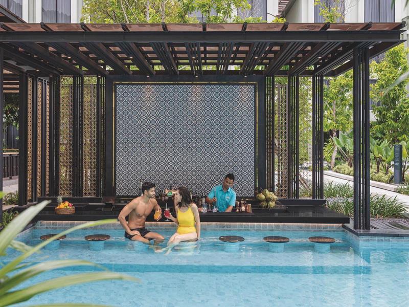 Ludzie relaksują się w basenie z zadaszonym miejscem do siedzenia obok hotelu.