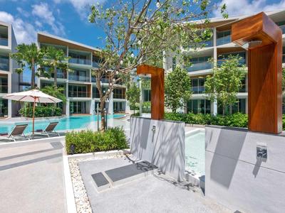 Docce esterne moderne con soffioni marroni accanto a una piscina e lettini in un complesso alberghiero.