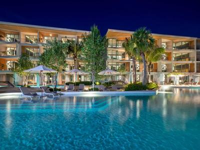 Edificio dell'hotel con piscina illuminata e palme di notte.